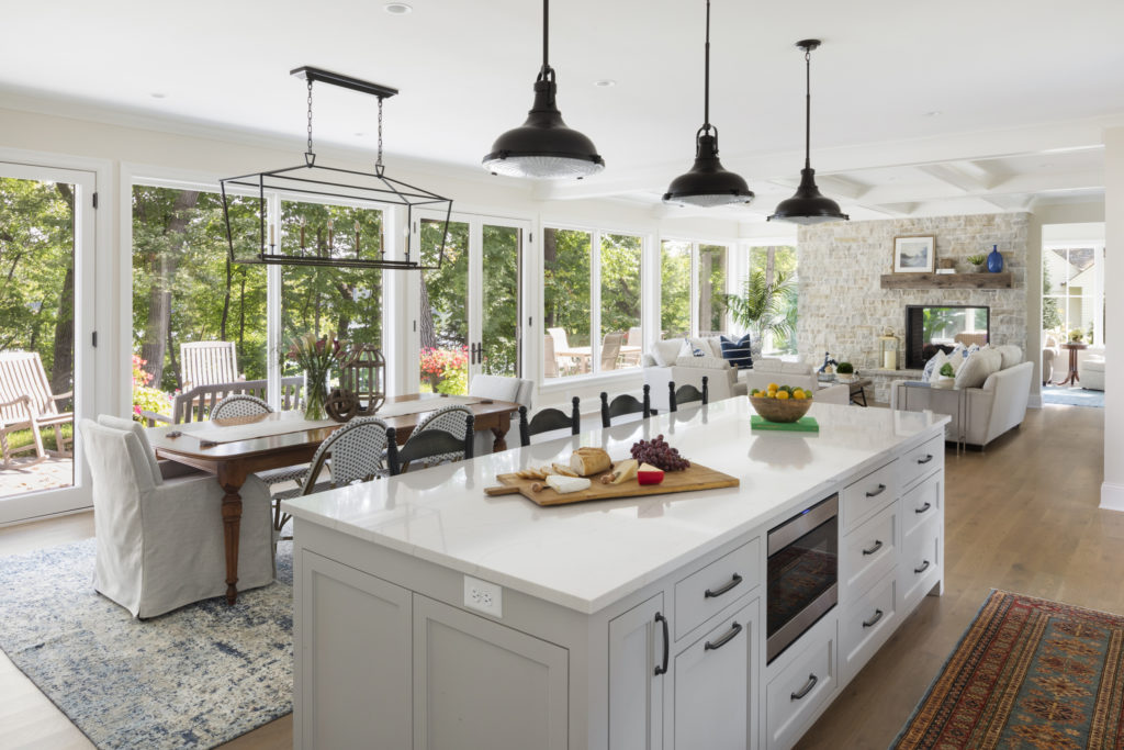 Open concept kitchen with while cabinetry and overhead lighting.