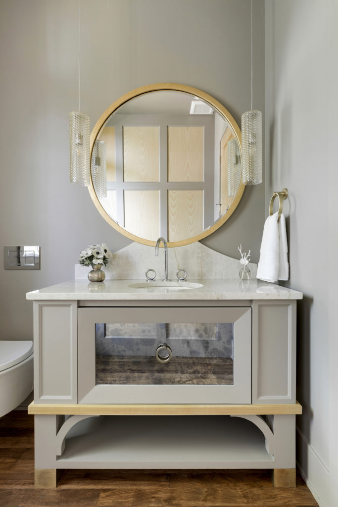 A large circular mirror on a custom stone vanity in a bathroom